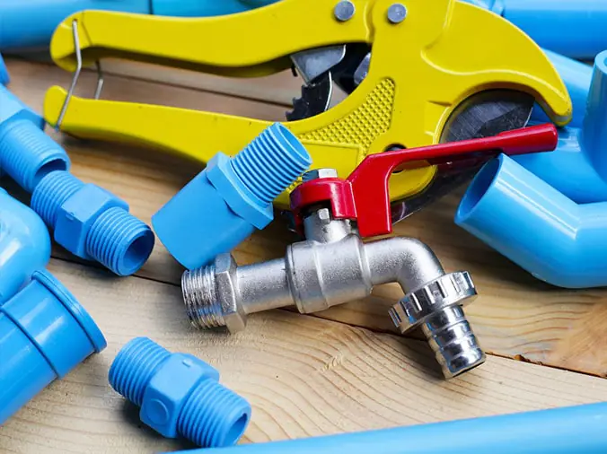 Blue PVC pipe fittings with a PVC cutting tool and stainkess faucet valve