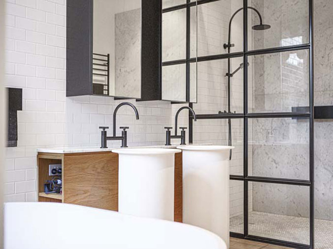 Bathroom with glas shower enclosure and black sink faucets and shower head